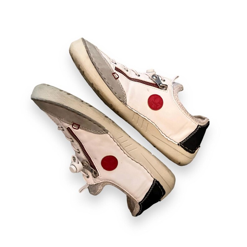 May include: A pair of white leather sneakers with red circle accents and zipper closures.