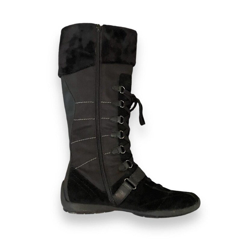 May include: Black suede knee-high boots with a zipper up the back and lace-up detail. The boots have a thick sole and a rounded toe.