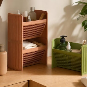 Tilt Stack angled storage: two-tier brown terracotta and green compact shelf bin with slatted fronts on a wooden vanity.