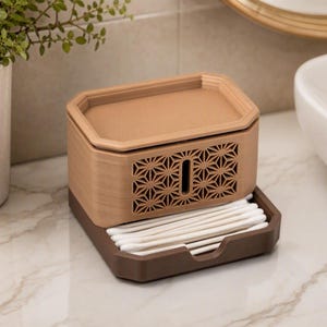May include: A two-toned rectangular storage container with a light tan top section featuring a geometric star pattern and a vertical slot. The base is a dark brown tray holding a row of white cotton swabs, providing a compact organization solution.