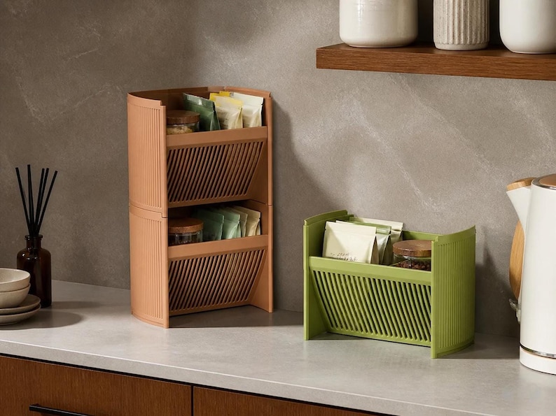 Tilt Stack stackable angled storage units in peach and olive green, two-tier with slatted fronts holding tea bags.