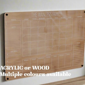 May include: A wooden calendar with the text "THE WANLESS FAMILY" at the top. The calendar has spaces for each day of the week and a section for notes. The calendar is available in acrylic or wood and multiple colors.