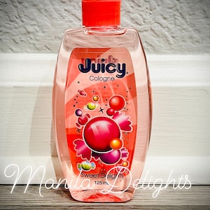 May include: A clear glass bottle of Juicy Cologne with a red cap and a pink and white label. The label says "Juicy Cologne" and "Sweet Delights" with a design of colorful candy and bubbles. The bottle contains 125 ml of cologne.