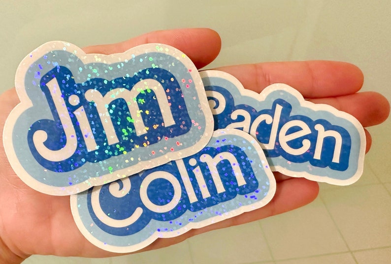 May include: Three blue and white iridescent glitter stickers with the names "Jim", "Colin", and "Jaden" written in white.