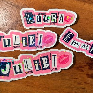 May include: Four pink and white stickers with glitter and black text. The stickers say "Laura Eat Me", "Juliet Eat Me", "Juliet Eat Me", and "Emma Eat Me".