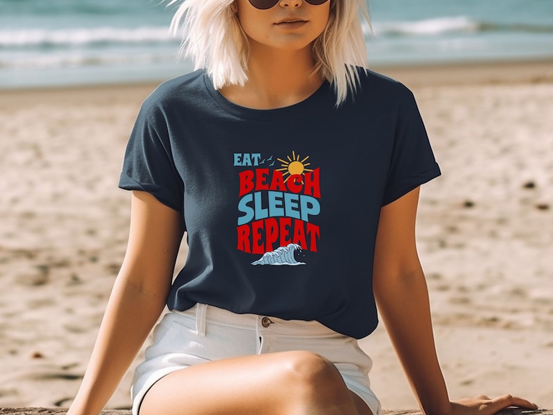 May include: A navy blue t-shirt with a white graphic that says "Eat, Beach, Sleep, Repeat" with a sun and a wave graphic.