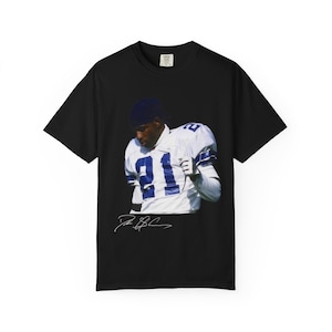 Pode incluir: Camiseta preta com uma fotografia de um jogador de futebol americano em uniforme branco e azul, com o número 81. A assinatura do jogador está abaixo da imagem. A camisa tem uma etiqueta na parte superior.