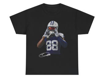 Op de afbeelding: Zwart t-shirt met een American footballspeler in een blauw-wit uniform, met nummer 88. De speler draagt een helm en houdt zijn gezichtsmasker vast. Onderaan staat een handtekening.