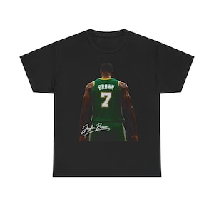 Puede incluir: Camiseta negra con una camiseta verde que muestra el nombre "BROWN" y el número "7". El nombre del jugador, "Jaylen Brown", también está impreso en la camiseta. La imagen es un primer plano de la parte posterior de la camiseta.