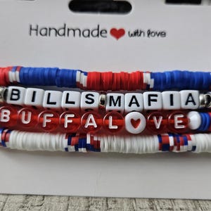 May include: Four stackable bracelets with red, white, and blue beads. The bracelets spell out "Bills Mafia" and "Buffalo Love" with white letter beads.