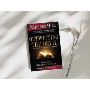 Op de afbeelding: Een boek getiteld "Outwitting the Devil: The Secrets to Freedom and Success" van Napoleon Hill, geannoteerd door Sharon Lechter met een voorwoord van Mark Victor Hansen.