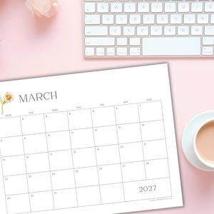 May include: A white paper calendar for March 2027 featuring a grid layout with black text and a small watercolor illustration of a daisy flower. The calendar includes days of the week and numbered dates from one to thirty-one in a clean design.