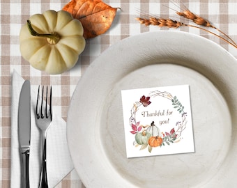 May include: A fall-themed table setting with a white plate, silverware, and a small pumpkin. A card on the plate reads "Thankful for you!" and features watercolor pumpkins and leaves. The tablecloth has a brown and white checkered pattern.