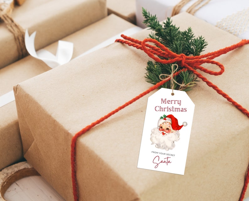 May include: A brown gift box with a red ribbon and a white gift tag. The gift tag has a vintage illustration of Santa Claus and the text "Merry Christmas" and "From your Secret Santa".