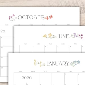 May include: Three white 2026 calendars with floral accents. The calendars display the months of October, June, and January. Each month is written in a dark grey font, with a floral design above the month's name.
