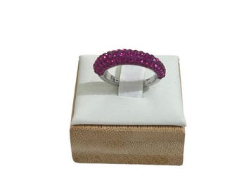 May include: A silver ring with a band of pink rhinestones on a small wooden ring display box.