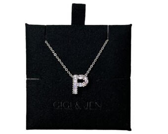 Può includere: Una collana d'argento con un ciondolo a forma di lettera P composto da diamanti a baguette. La collana è esposta in un cofanetto per gioielli in velluto nero con la scritta "Gigi & Jen" stampata sul davanti.