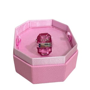 May include: A pink gemstone ring with a silver band. The ring is in a pink box.