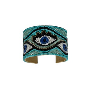May include: A turquoise blue beaded cuff bracelet with a black and white evil eye design. The bracelet is made of small beads and has a gold accent.