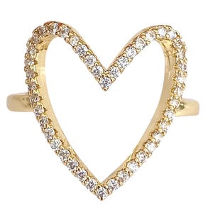 May include: A gold ring with a heart-shaped design. The heart is outlined with small, clear stones.