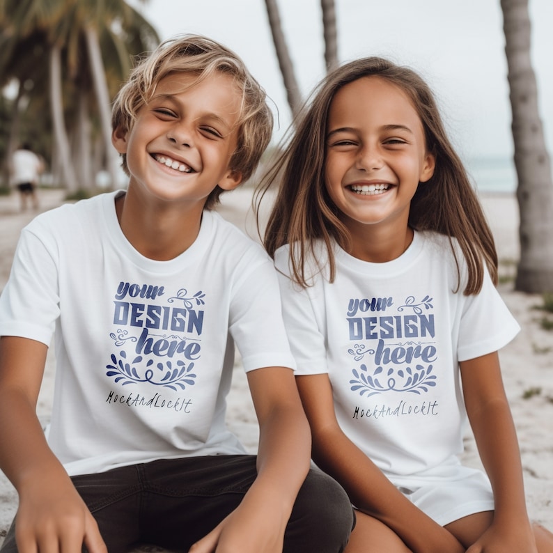 May include: Two children wearing white t-shirts with the text "your design here" and "MockAndLockIt" printed on them. They are sitting on a sandy beach with palm trees in the background.