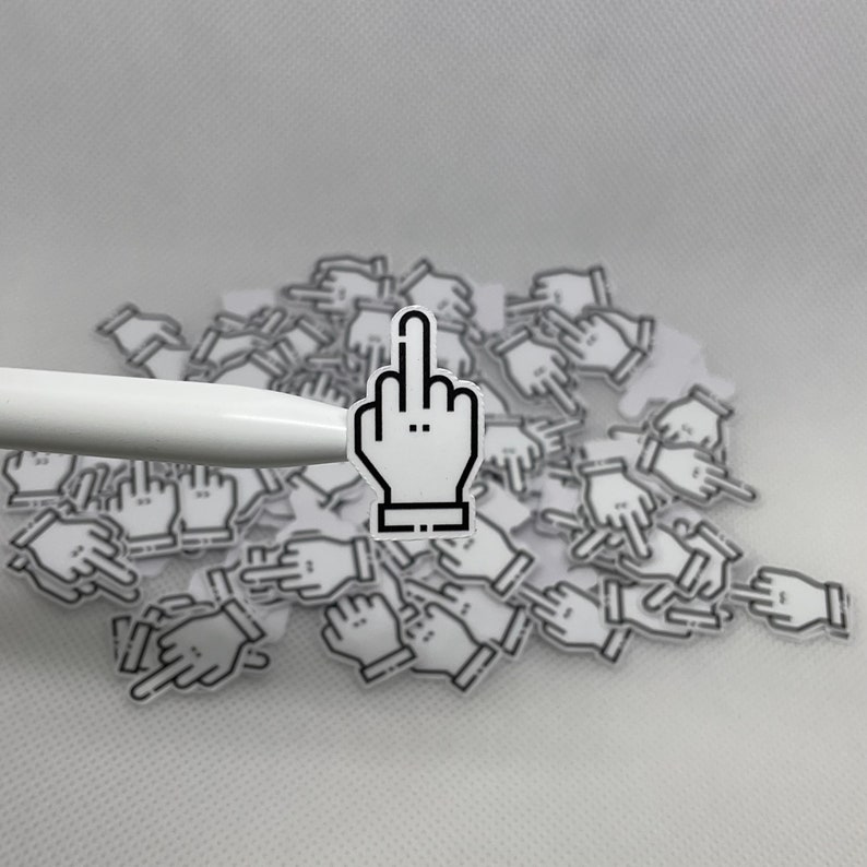May include: A white background with a pile of black and white stickers of a hand giving the middle finger. The stickers are scattered on the surface.