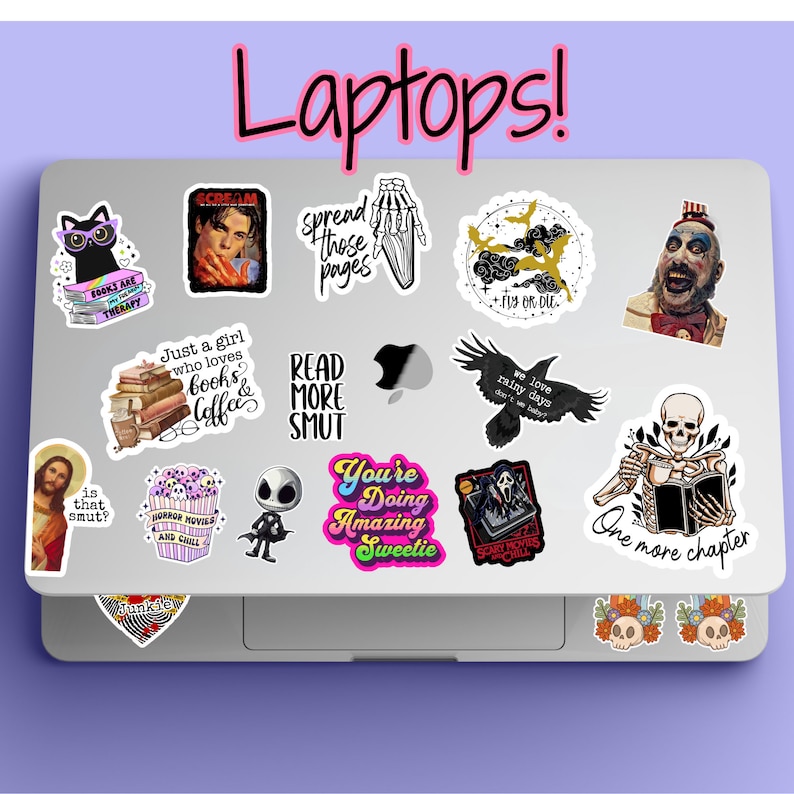 May include: A silver laptop computer with various colorful stickers on the lid. The stickers feature images and text, including "Scream", "Spread those pages", "Read More Smut", "You're Doing Amazing Sweetie", "We love rainy days", "One more chapter", "Horror Movies and Chill", "Just a girl who loves books & coffee", "Fly or Die", and "Scary Movies & Chill".