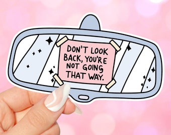 May include: A blue and white cartoon rearview mirror sticker with a pink note that says "Don't look back, you're not going that way."