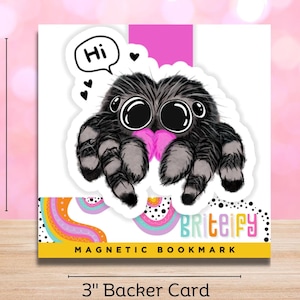 May include: A cute cartoon spider holding a pink heart with the word "Hi" in a speech bubble above it. The image is a magnetic bookmark with the text "Briteify" and "MAGNETIC BOOKMARK" below the spider.