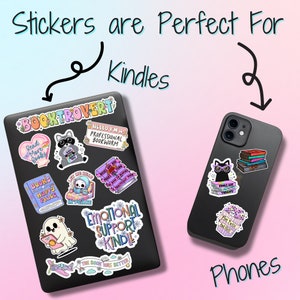 May include: A collection of colorful stickers featuring book-themed illustrations and text, such as "Read More Books", "Books Are Therapy", and "Emotional Support Kindle". The stickers are shown on a black Kindle and a black smartphone.