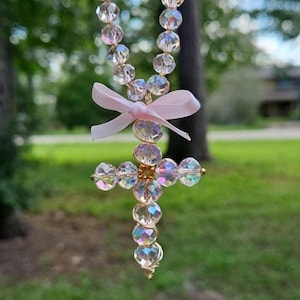May include: A crystal beaded necklace with a pink ribbon and a crystal cross pendant.