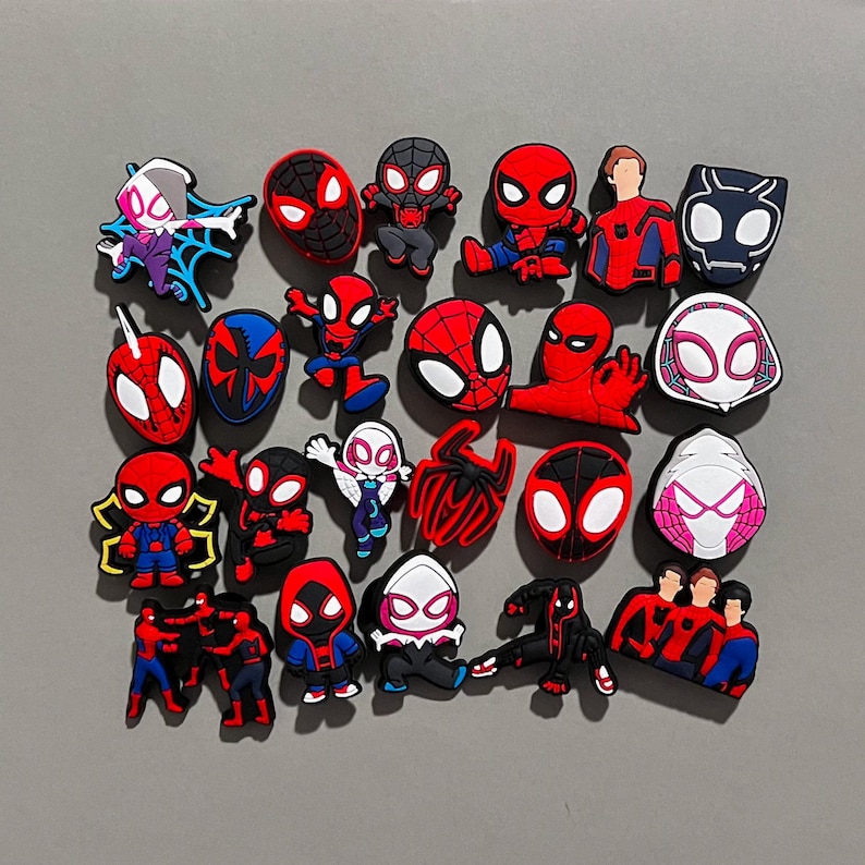 May include: A collection of 20 colorful cartoon Spider-Man character shoe charms. The charms feature different versions of Spider-Man, including Spider-Gwen, Miles Morales, and the classic red and blue Spider-Man.