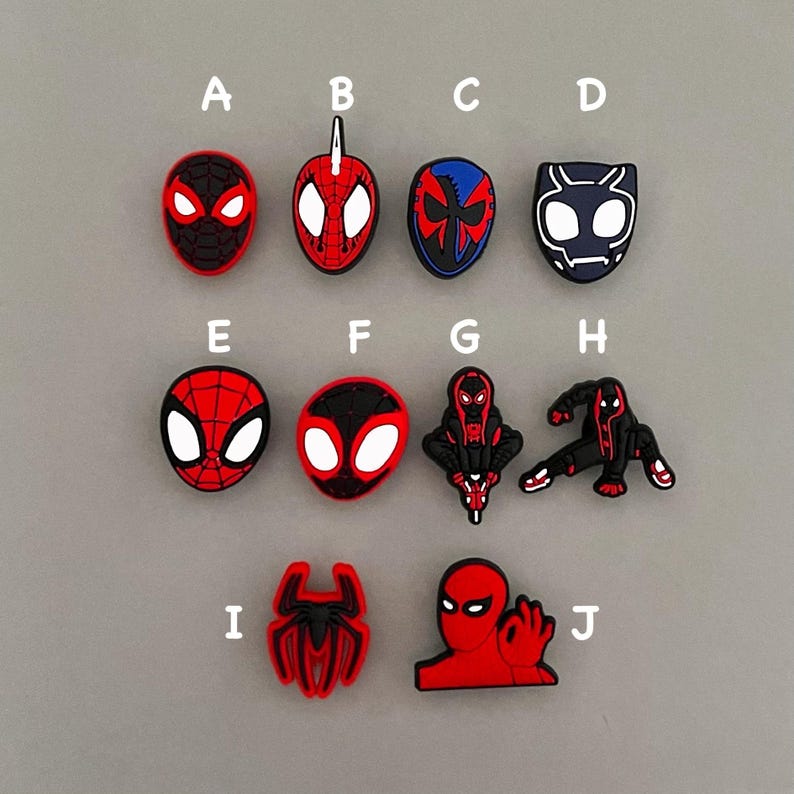 May include: Ten different Spider-Man themed shoe charms, each featuring a different design of the superhero in red, black, and white. The charms are labeled A through J.