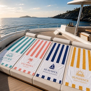 May include: Four striped beach towels on a yacht deck. The towels are white with vertical stripes in teal, coral, navy, and yellow. Each towel has a resort logo: Azure Beach Club, Palmora Resort, Seavista Hotels & Resorts, and Sundance Beach Resort.