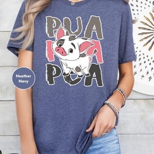 A person wearing a blue t-shirt with a cartoon pig graphic and text on it.