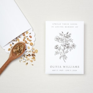 May include: A white card with black text that reads "Spread these seeds in loving memory of Olivia Williams May 17, 1923 - June 5, 2024". A black and white illustration of a flower bouquet is in the centre of the card.