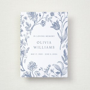 May include: A rectangular memorial card with a blue floral design. The card features the text "In Loving Memory", the name "Olivia Williams", and the dates "May 17, 1923 - June 5, 2024".