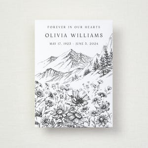 May include: A white memorial canvas print with a black and white mountain and floral illustration. The text reads "Forever in Our Hearts" and the name "Olivia Williams" with birth and death dates. The artwork features a detailed mountain range and a field of flowers.