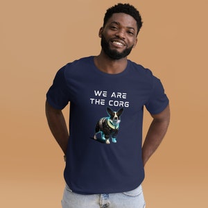 May include: A navy blue t-shirt with a white graphic of a corgi wearing a futuristic suit. The text "WE ARE THE CORG" is printed in white above the image.