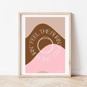 Puede incluir: Una impresión enmarcada con un diseño abstracto rosa y marrón. La impresión presenta un círculo blanco con el texto "Feel the Burn" repetido alrededor del círculo.
