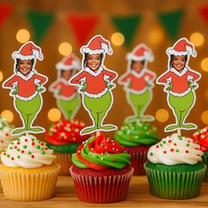 May include: Festive cupcakes with white, green, and red frosting, topped with Grinch-themed character cutouts. The cupcakes are arranged on a wooden surface, with a blurred background of lights and holiday bunting.