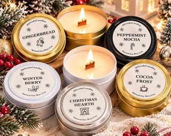 Könnte beinhalten: Eine Sammlung von fünf runden Metalldosen für Kerzen mit Deckeln, beschriftet mit Gingerbread, Peppermint Mocha, Winter Berry, Christmas Hearth und Cocoa Frost. Jede Dose enthält natürliches Sojawachs und einen Holzdocht, gekennzeichnet mit 4 oz.