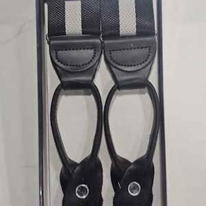 May include: Black and white striped suspenders with black leather accents. The suspenders are packaged in a clear box and feature the "BROOKS BROTHERS FACTORY STORE" logo.