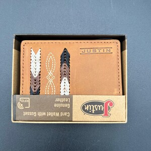 May include: A brown leather card wallet with decorative stitching in white, brown, and black. The wallet is in a cardboard box with the brand name "Justin" printed on the wallet and box.