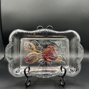 Może przedstawiać: Zestaw trzech ceramicznych kubków z nakrapianą, kremową glazurą. Każdy kubek ma inny ręcznie malowany wzór: niebiesko-zielony liść, żółty kwiat i czerwona jagoda. Kubki mają prosty, nowoczesny design.