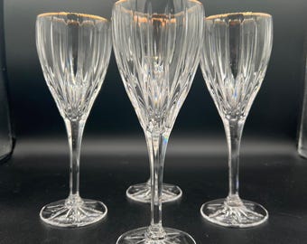 Può includere: Tre flûte da champagne in cristallo trasparente con bordi dorati. Le flûte hanno un design a coste verticali e poggiano su una base a forma di stella. I bicchieri sono eleganti e adatti alle occasioni speciali.