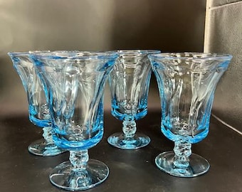 Puede incluir: Juego de cuatro copas de vidrio azul con diseño acanalado. Las copas tienen una base de vidrio transparente y un tallo.