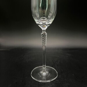 May include: A clear wine glass with a twisted stem and a circular base. The glass is designed for serving wine. The stem has a decorative, twisted design. The glass is made of clear glass and reflects light.