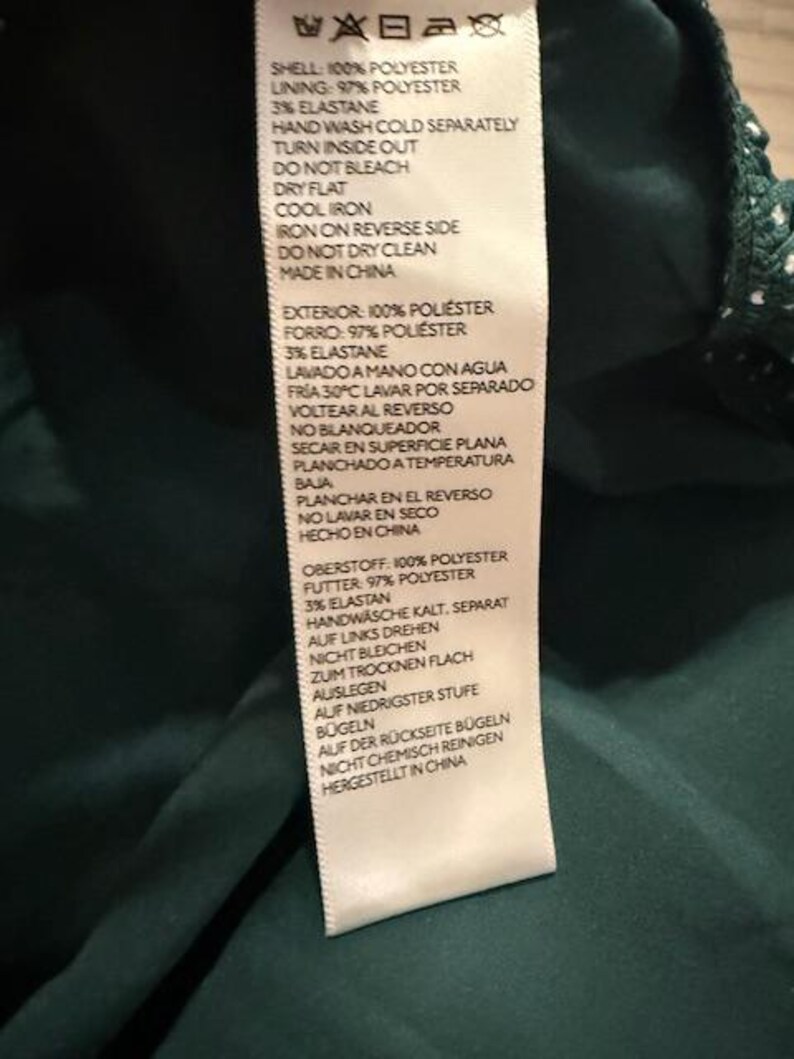 May include: A white care label with black text detailing the care instructions for a garment. The label includes instructions for washing, drying, ironing, and dry cleaning. The label also states that the garment is made in China.