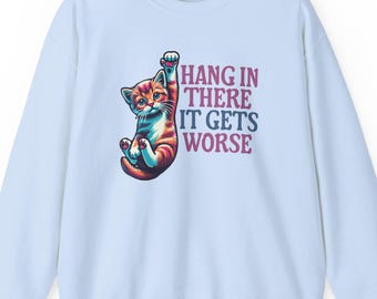 May include: Light blue sweatshirt with a graphic of a cat hanging upside down and the text "Hang in there it gets worse".